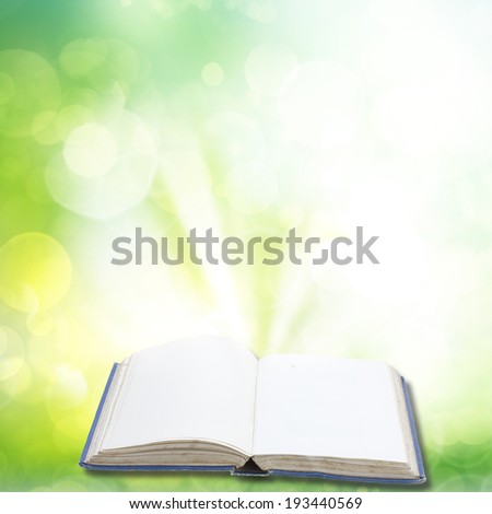 Open book in green garden  with light