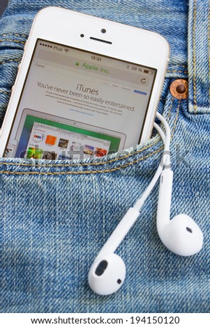 WARSZAWA, POLAND - APRIL 17, 2014: Iphone 5s in jeans pocket with Itunes page. iTunes is a media player, media library, and mobile device management application developed by Apple Inc.
