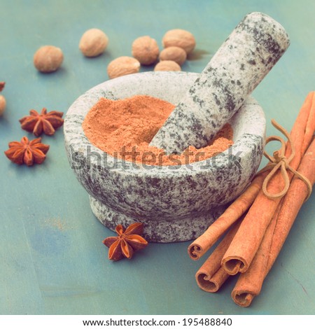 cinnamon powdered in mortar  with anise and nutmeg on wooden table
