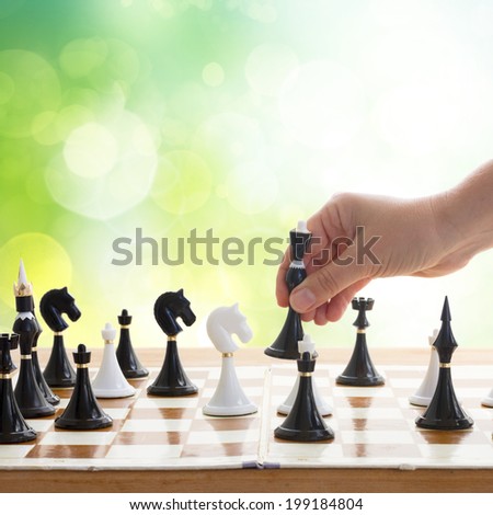 hand making move in chess game with black queen in green garden