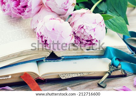 pile of vintage old books with pink  flowers and key stacked on table