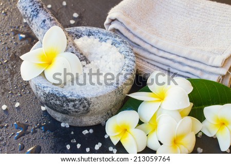Spa and wellness setting with natural sea sat,  towels  and  frangipani  flowers