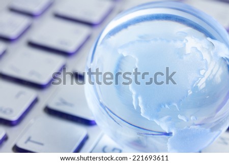 global computer business concept with small globe on laptop keyboard