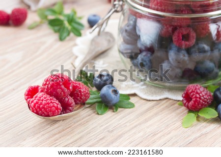 spoon of fresh raspberries   and blue berries on wooden table