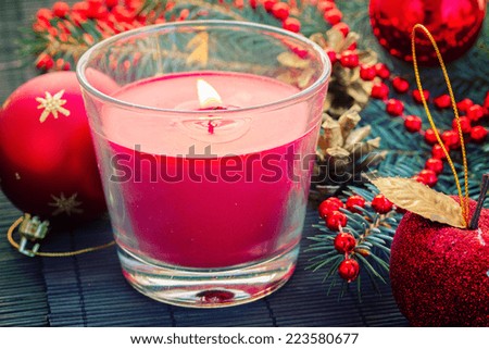 christmas  glowing red candle  with pile of decorations, retro toned