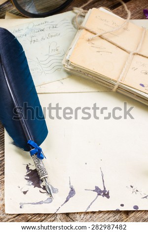 old blank paper with pile of  old letters and blue  feather pen