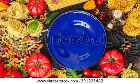 Raw pasta with ingridients and copy space on empty blue plate