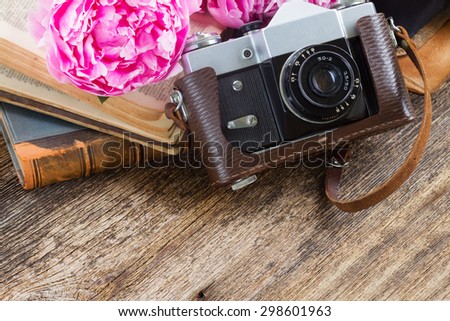 retro  photo camera with books and fresh pink  peony flowers