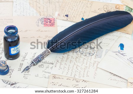 blue  feather pen and inkwell on  old papers and  letter background