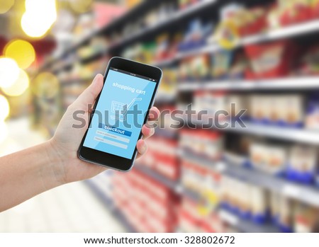 someones  hand holding mobile smart phone with mobile shop  on supermarket blur background  - e-commerce concept