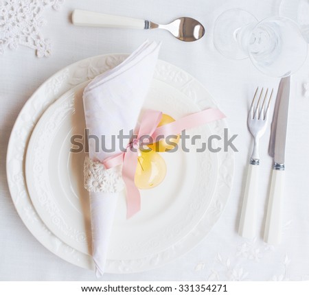 Plates, napkin and utensils on white tablecloth with christmas decorations