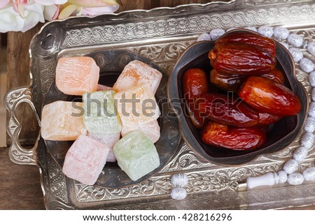 Turkish delights Lokum and date fruits with tasbih on silver oriental tray, top view