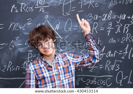 Boy in glasses, blackboard filled with math formulas background