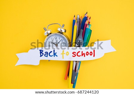 back to school concept - alarm clock and school supplies with back to school text on ribbon
