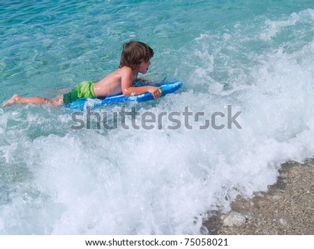 Little boy learning surf in sea