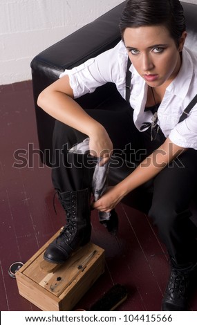 A young woman shines up her old boots shoe shine