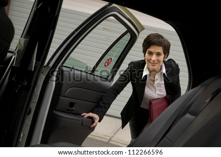 A business woman gets in the back seat of taxi cab downtown urban traveler