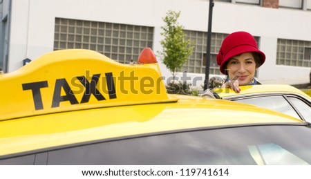 A beautiful woman traveler gets in the yellow taxi cab downtown