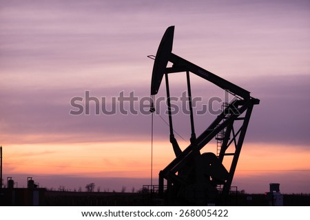 A lonely Pump Jack sits working oil fields at sunset in North Dakota, USA