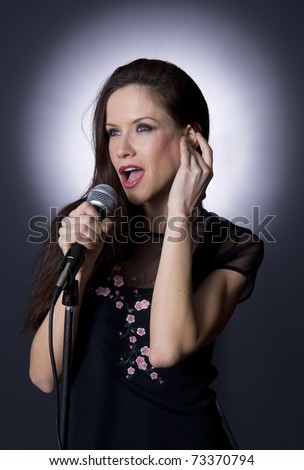 Female Vocalist Singing Song into Microphone Under Spotlight Entertainment Performance