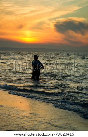 Fisherman Casts out into Ocean on Beach at Sunset