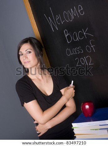 A Beautiful Woman teacher welcomes her students back to the classroom blackboard education
