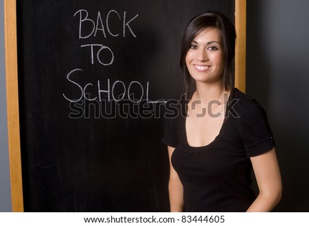 Teacher\'s Class Room female stands by blackboard welcome student back to school