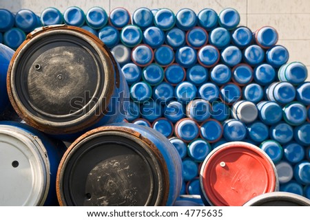 plastic barrels with big pile of stacked blue barrels in background