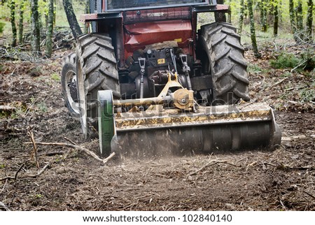 tractor forest clearing in the woods with a brush-cutter