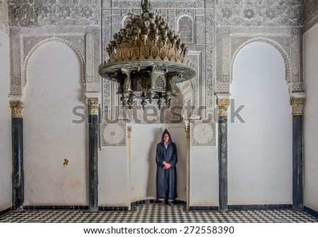 Fes, Morocco - May 11, 2013: Man in berber clothing in an alcove in the inner courtyard of the 14th century  El Attarine Medersa in Fez, Morocco