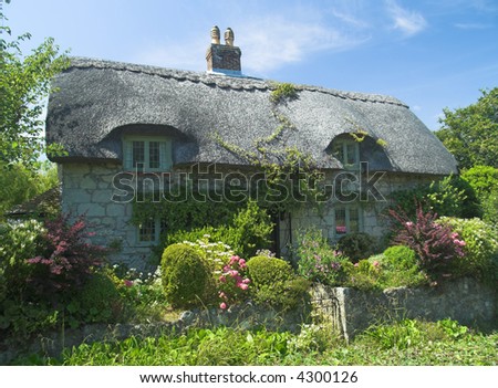 Typical English rural cottage with thatched roof and garden
