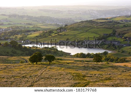 warm evening sunlight warms the landscape around a yorkshire reservoir in the heart of bronte country.