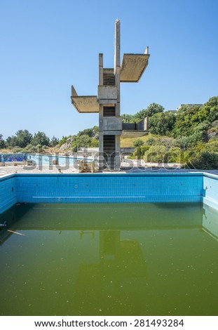 an abandoned lido complex on the island of rhodes in Greece where the swimming pools have filled with rain water and tuend green with algae