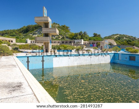 an abandoned lido complex on the island of rhodes in Greece where the swimming pools have filled with rain water and tuend green with algae