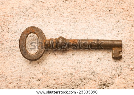 old oxidized iron key on stone background