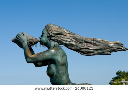 long hair mermaid blowing a shell against the wind