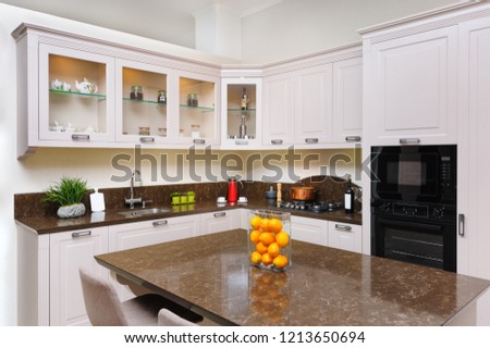 Luxury cozy modern light beige kitchen, embedded microwave and electric oven, gas stove, minimalistic clean design
