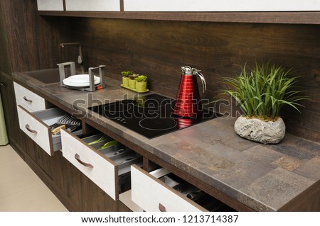 Luxury cozy modern dark brown kitchen, induction stove, minimalistic clean design. some drawers are open