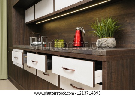 Luxury cozy modern dark brown kitchen, induction stove, minimalistic clean design. some drawers are open