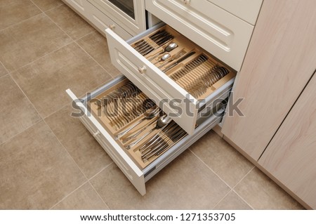 Opened kitchen drawers with silverware sets, high angle view