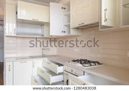 Modern classic spacioius cream colored kitchen, some drawers and trays are open