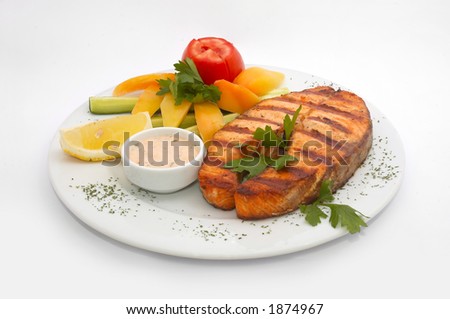 served grilled sturgeon fish with fresh vegetables: yellow pepper, cucumber an d tomato and parsley
