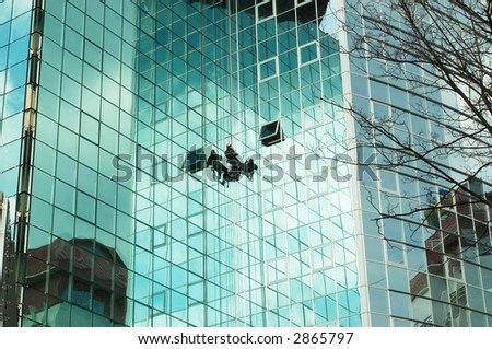 worker climbing at mirror wall of office building