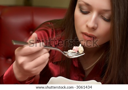 Beautiful brunette in red eats salad. Selective focus (mouth).