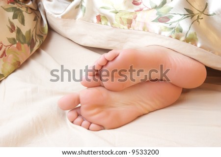 sleeping woman\'s cute feet, blanket over legs