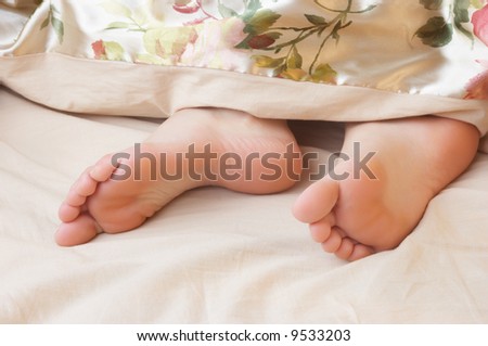 sleeping woman\'s cute feet, blanket over legs