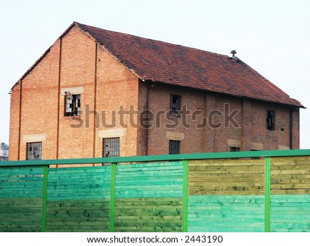 Old red brick building and green fence