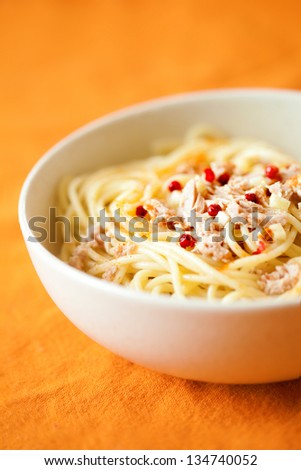 Spicy tuna pasta with red peppers, garlic and chili powder shot on orange fabric