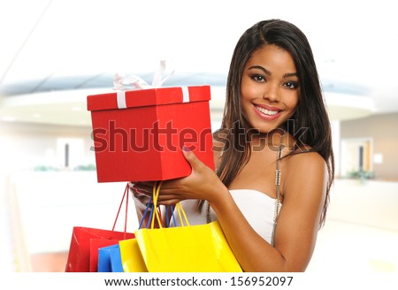Young Black woman holding bags and a box inside a mall