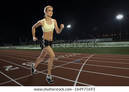 Woman running on a track at night
